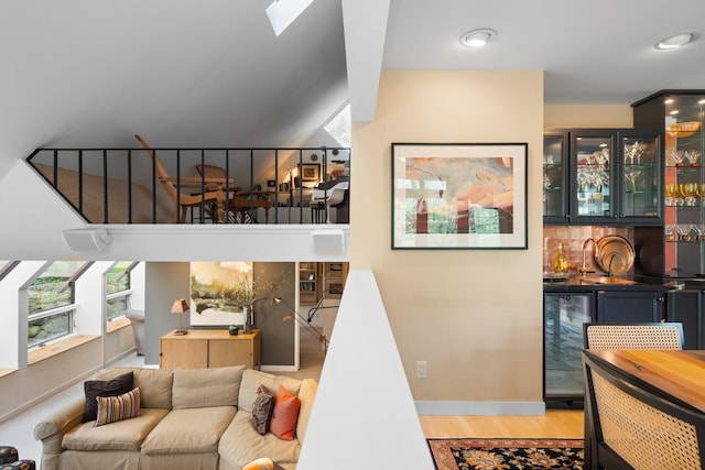 living room featuring wet bar, wine cooler, light wood-style flooring, and baseboards
