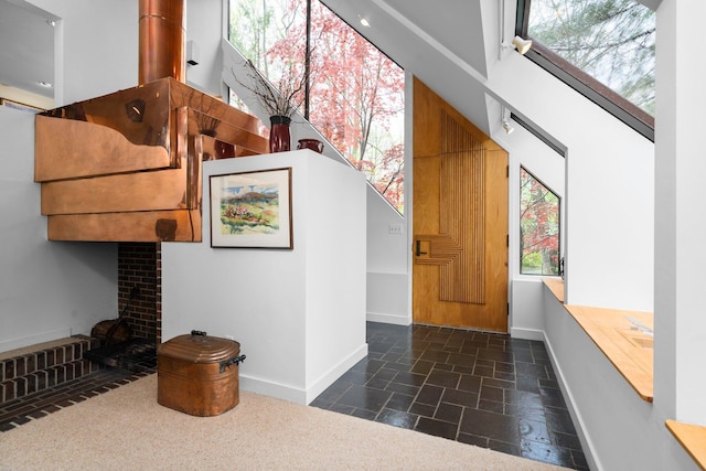 entryway featuring stone tile flooring, baseboards, and a brick fireplace