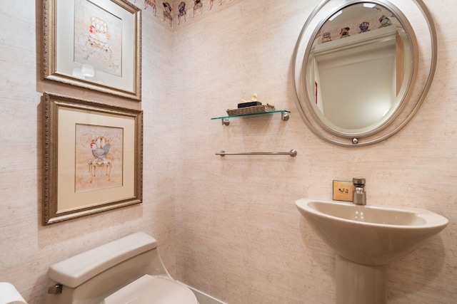 half bath with toilet, tile walls, and a sink