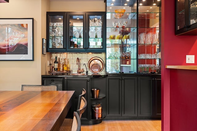indoor wet bar with tasteful backsplash and light wood-style flooring