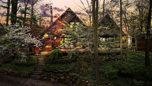 property exterior at dusk featuring stairway and a wooden deck