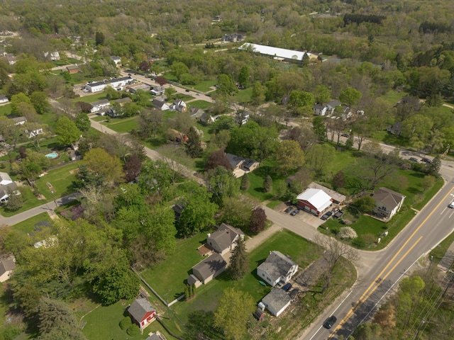 aerial view of property and surrounding area featuring nearby suburban area and a heavily wooded area