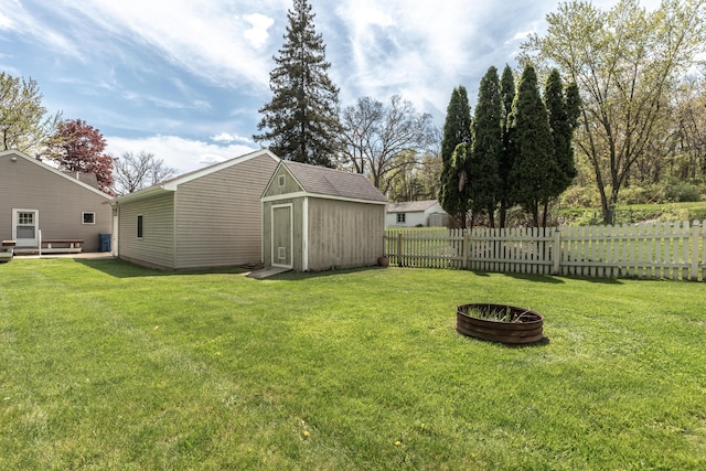 view of yard with a storage unit, an outdoor structure, and an outdoor fire pit