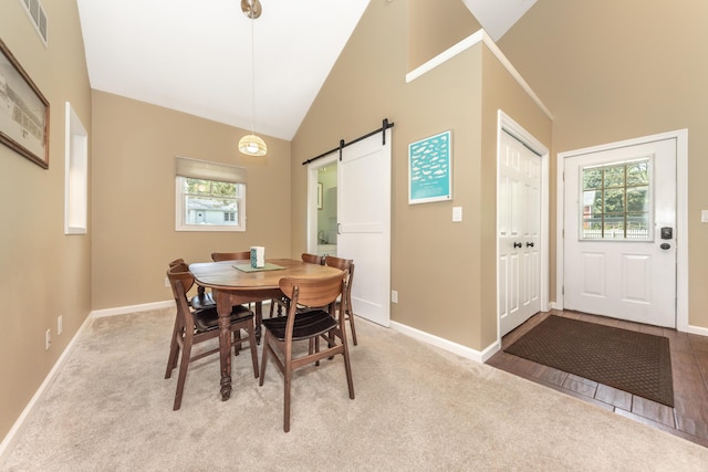 carpeted dining area featuring a barn door, baseboards, and high vaulted ceiling