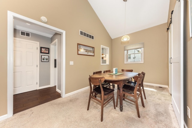 dining area featuring carpet, baseboards, high vaulted ceiling, and a barn door