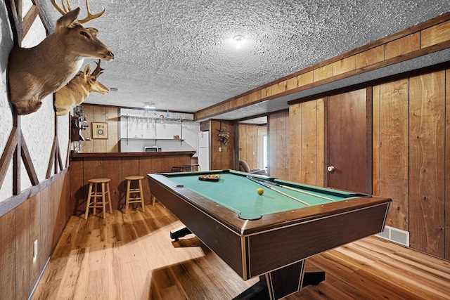 2394 Cedar Crest Dr NE, Grand Rapids, MI 49525 - game room featuring a bar, wood finished floors, wood walls, billiards, and a textured ceiling