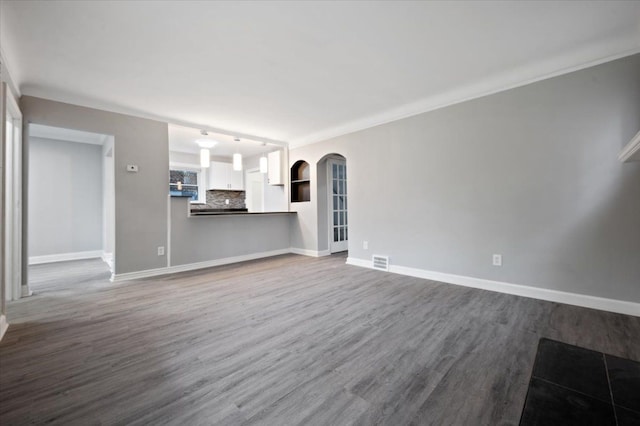 unfurnished living room with dark wood-style flooring, baseboards, arched walkways, and ornamental molding