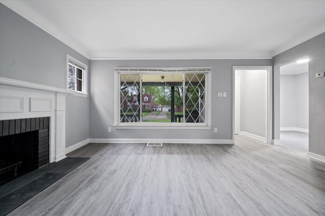 unfurnished living room featuring wood finished floors, baseboards, and a brick fireplace