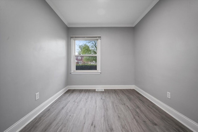 unfurnished room featuring wood finished floors, baseboards, and ornamental molding
