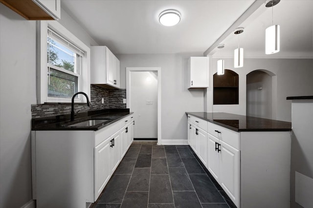 kitchen featuring a sink, tasteful backsplash, white cabinets, and baseboards