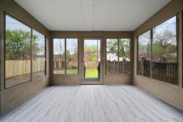 unfurnished sunroom featuring wood finished floors and healthy amount of natural light