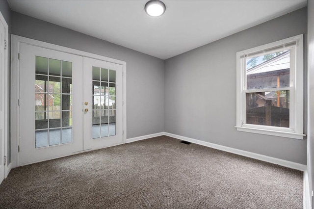 empty room featuring french doors, dark colored carpet, and baseboards