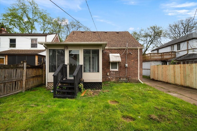 rear view of house with a sunroom, brick siding, and a shingled roof
