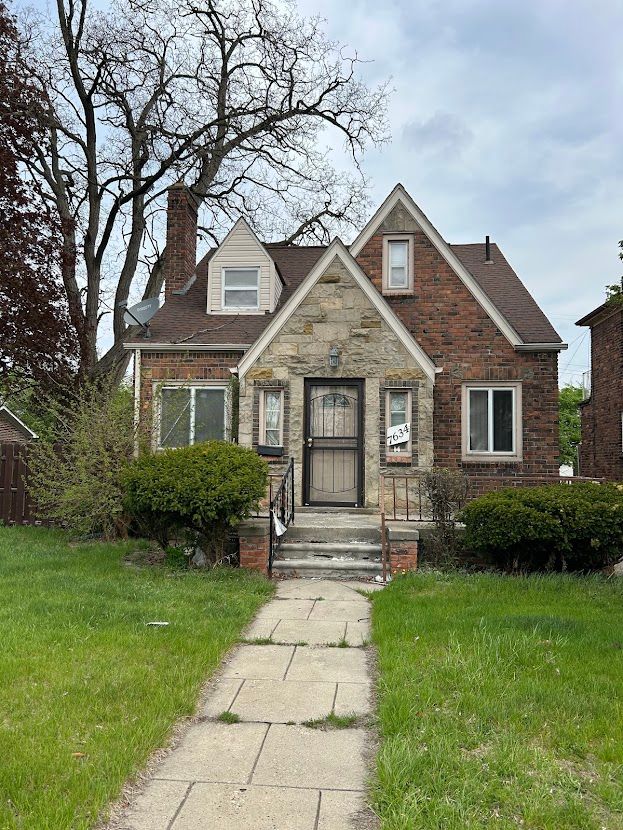 view of front of house with a chimney, brick siding, stone siding, and roof with shingles