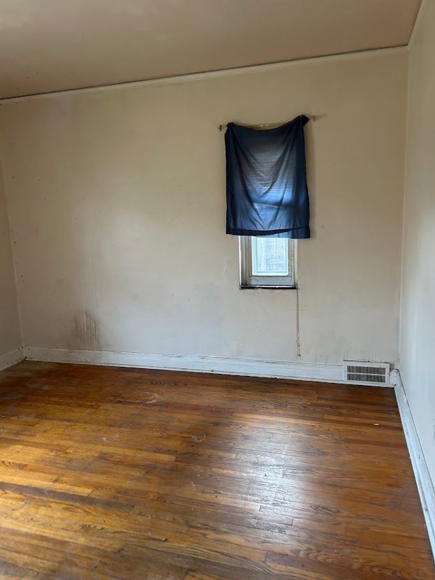 spare room with hardwood / wood-style floors and baseboards