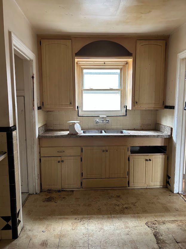 kitchen featuring a sink, backsplash, and light brown cabinets