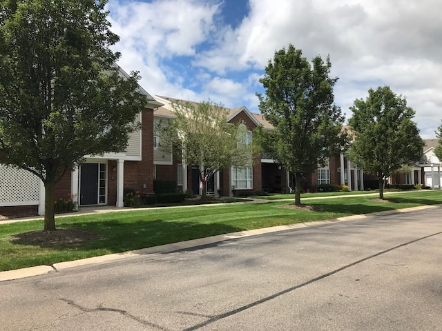 obstructed view of property featuring brick siding and a front lawn