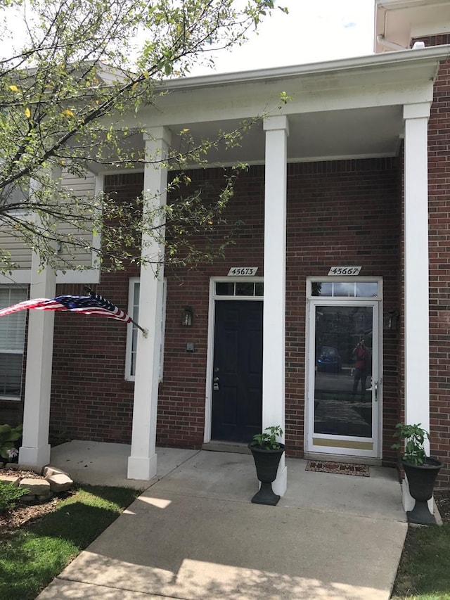 doorway to property with brick siding and a porch