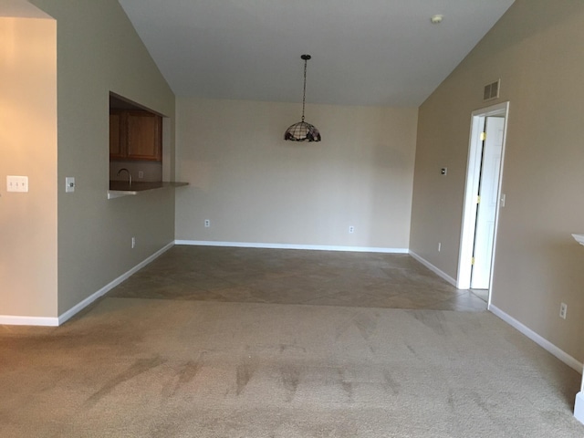 carpeted spare room featuring lofted ceiling, baseboards, and a sink