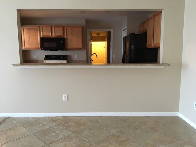 kitchen featuring black appliances, baseboards, a peninsula, light countertops, and a sink