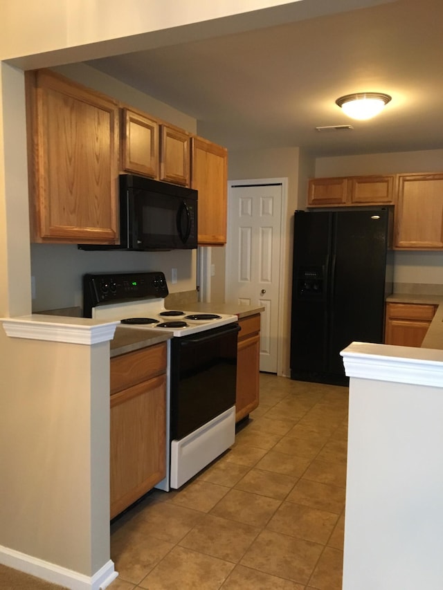 kitchen featuring black appliances, light tile patterned floors, and light countertops