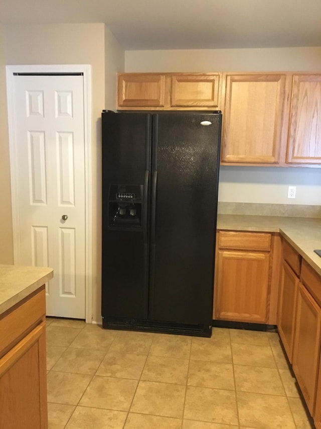 kitchen with black fridge, light countertops, and light tile patterned floors