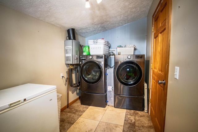 washroom with washing machine and clothes dryer, a textured ceiling, and baseboards