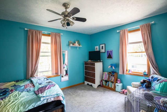 carpeted bedroom with a textured ceiling, ceiling fan, and baseboards