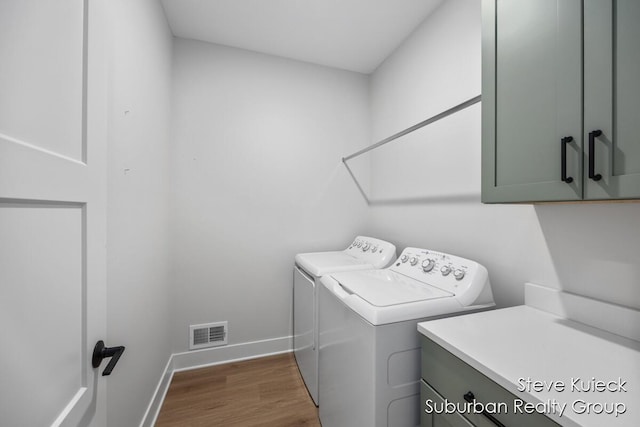 laundry area featuring cabinet space, washer and clothes dryer, baseboards, and wood finished floors