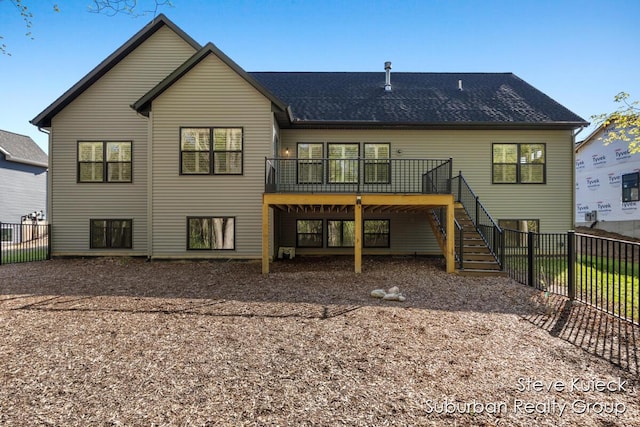rear view of property featuring stairway, a wooden deck, and a fenced backyard