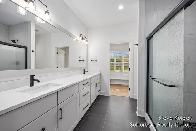 bathroom with a stall shower, double vanity, recessed lighting, baseboards, and tile patterned flooring