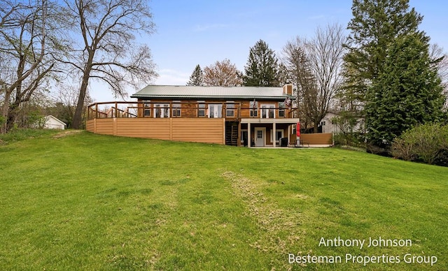 back of house with a wooden deck, a yard, a chimney, and metal roof