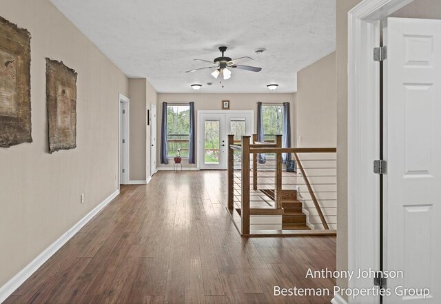 corridor with hardwood / wood-style flooring, baseboards, a textured ceiling, and french doors