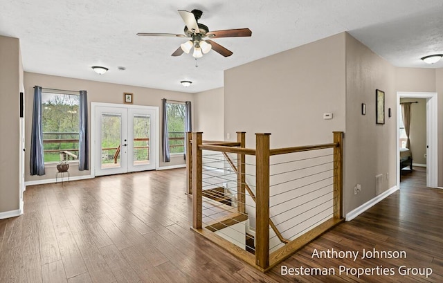 hall featuring an upstairs landing, wood finished floors, baseboards, french doors, and a textured ceiling