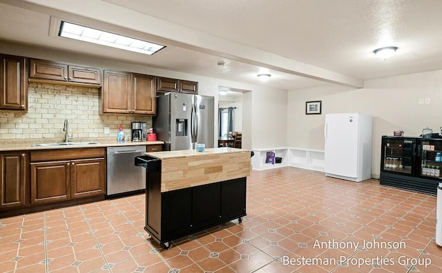 kitchen with stainless steel appliances, a sink, backsplash, and a kitchen island