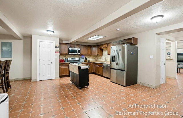 kitchen featuring stainless steel appliances, light countertops, a sink, electric panel, and baseboards