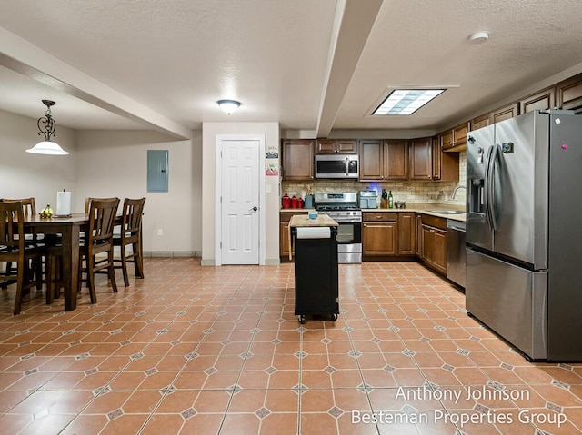 kitchen with stainless steel appliances, a sink, light countertops, decorative backsplash, and electric panel