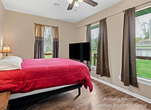 bedroom with multiple windows, baseboards, wood finished floors, and a ceiling fan