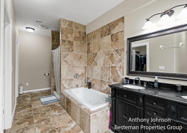 bathroom featuring stone finish floors, a tub with jets, tiled shower, double vanity, and baseboards