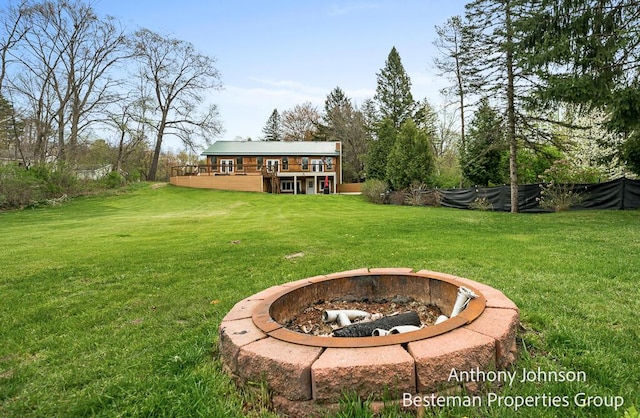 view of grassy yard featuring a fire pit and a wooden deck