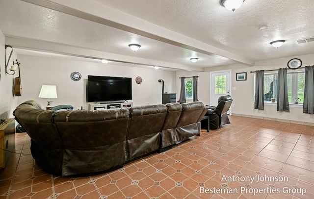 tiled living area featuring a textured ceiling, baseboards, and beamed ceiling