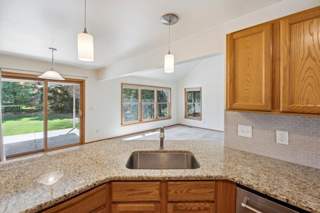 kitchen with a sink, stainless steel dishwasher, tasteful backsplash, brown cabinets, and light stone counters
