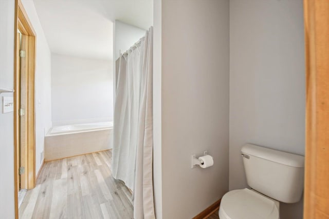 bathroom with wood finished floors, toilet, tiled bath, and a shower with shower curtain