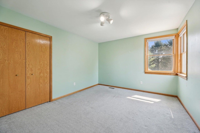 unfurnished bedroom featuring carpet, baseboards, and a closet