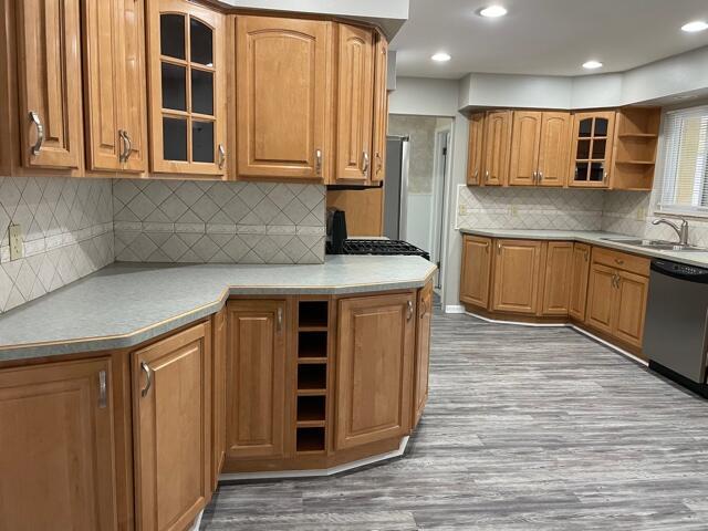 kitchen featuring a sink, open shelves, dishwasher, wood finished floors, and brown cabinetry