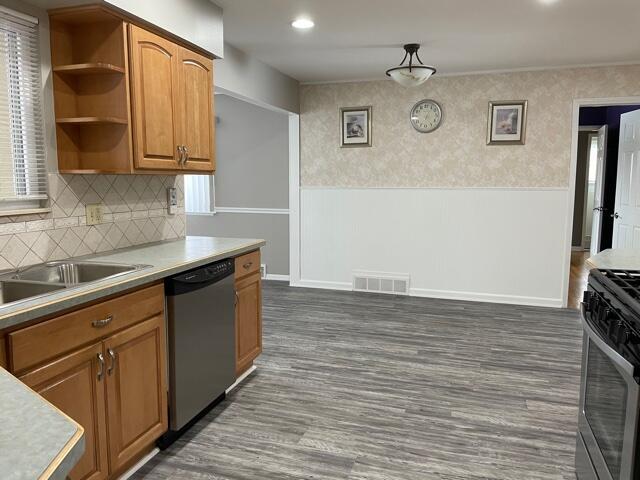 kitchen with appliances with stainless steel finishes, wainscoting, open shelves, light countertops, and dark wood-style flooring