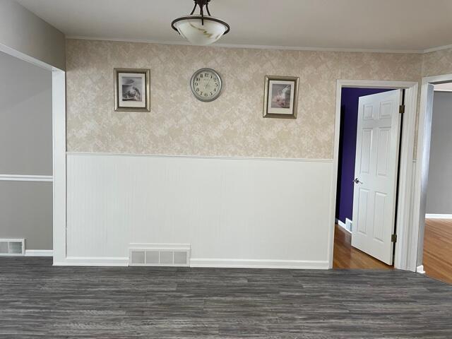 unfurnished dining area with dark wood-style flooring, baseboards, and a wainscoted wall