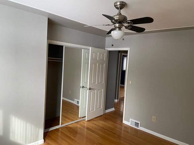 unfurnished bedroom featuring wood finished floors, baseboards, a closet, and a ceiling fan