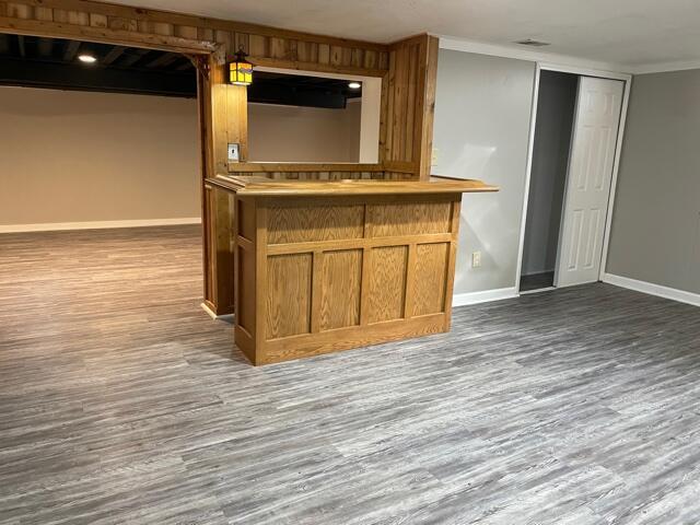 detailed view of wood finished floors, baseboards, a bar, and ornamental molding