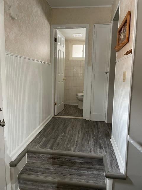 corridor with a wainscoted wall and wood finished floors
